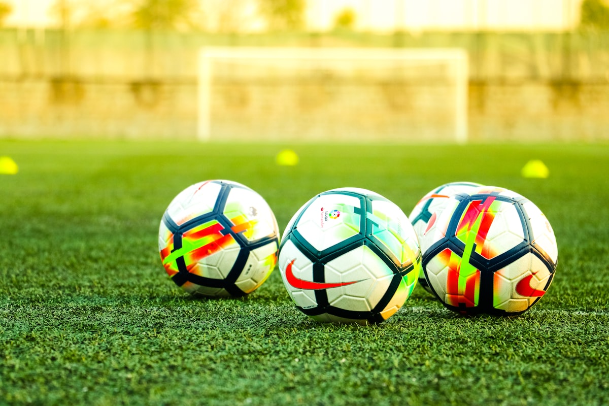 Footballs lined up in front of a goal at training